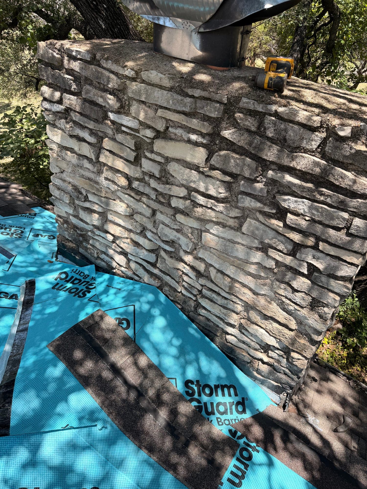 GAF StormGuard leak barrier run around the base of a stone chimney before any flashing metal goes on