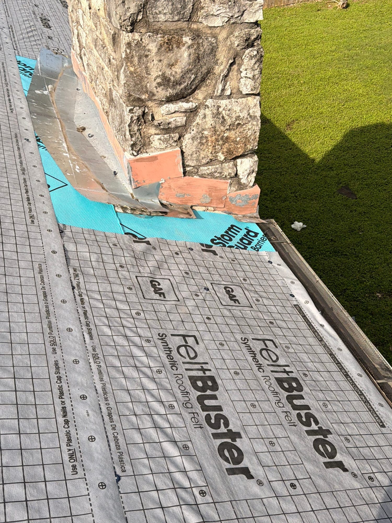Stone chimney with counterflashing cut in over StormGuard leak barrier and FeltBuster underlayment