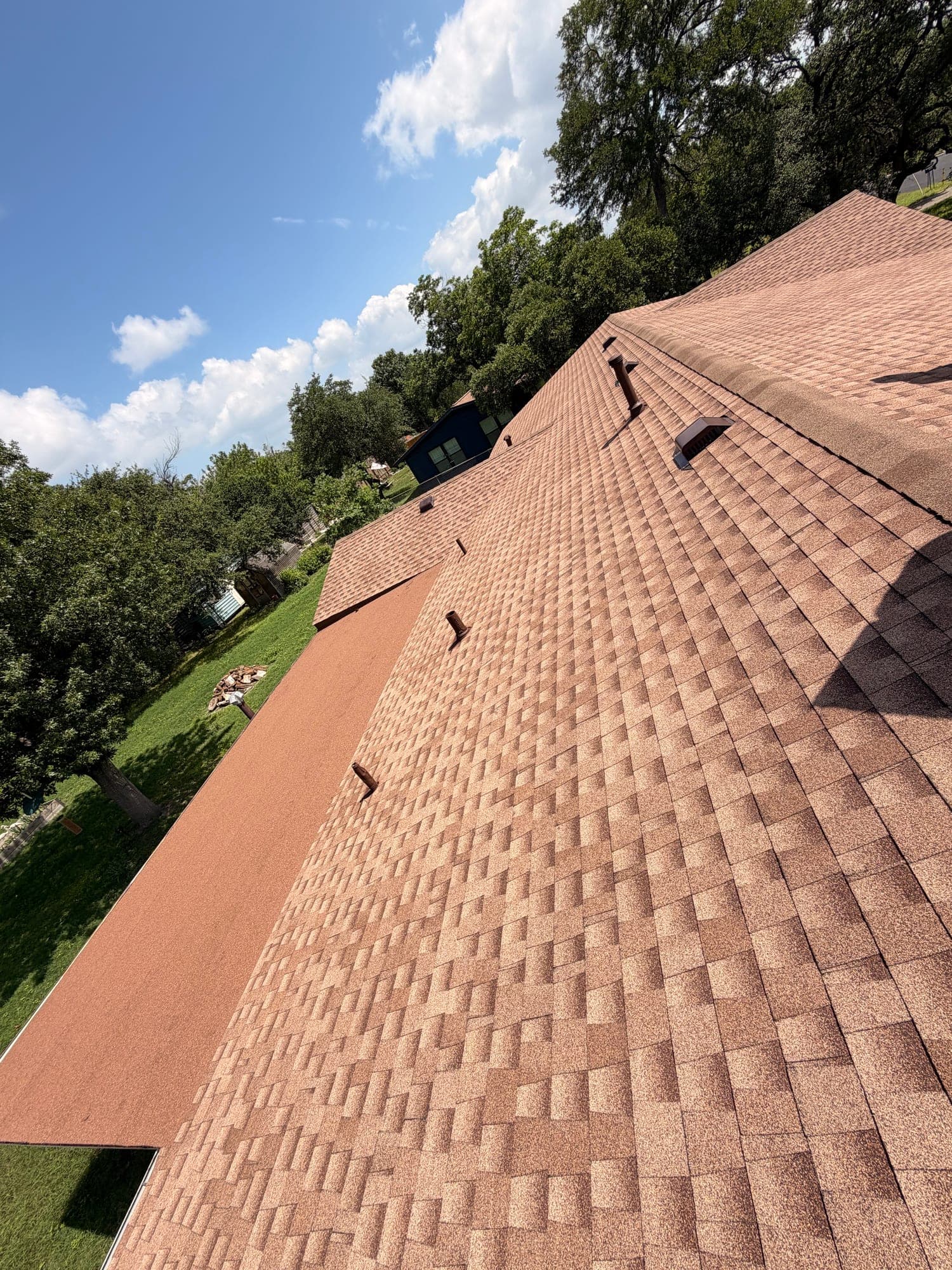 Large finished expanse of tan architectural shingle with static vents set along the slope