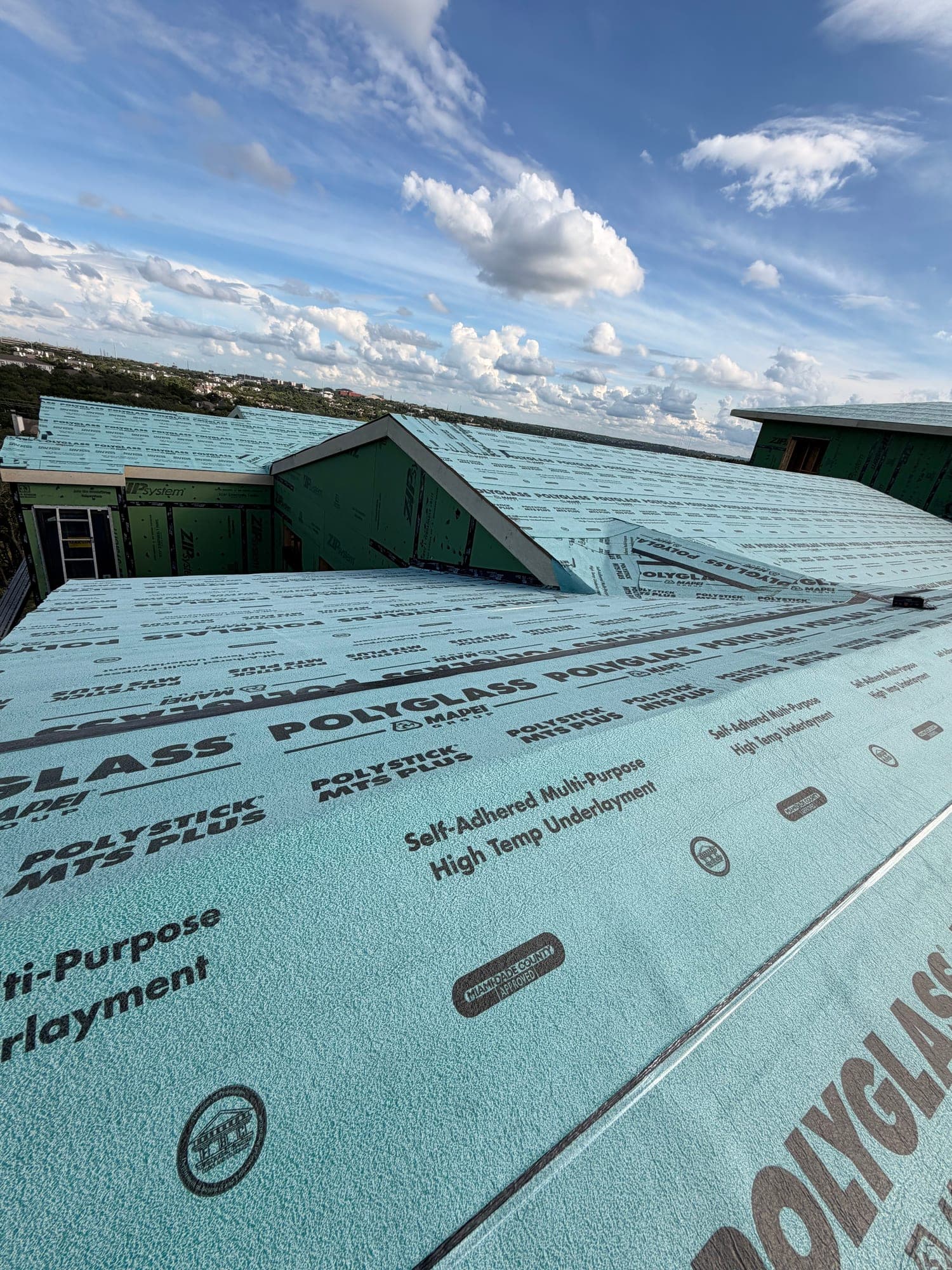 Polyglass Polystick MTS Plus self-adhered high-temp underlayment covering a new build roof against blue sky