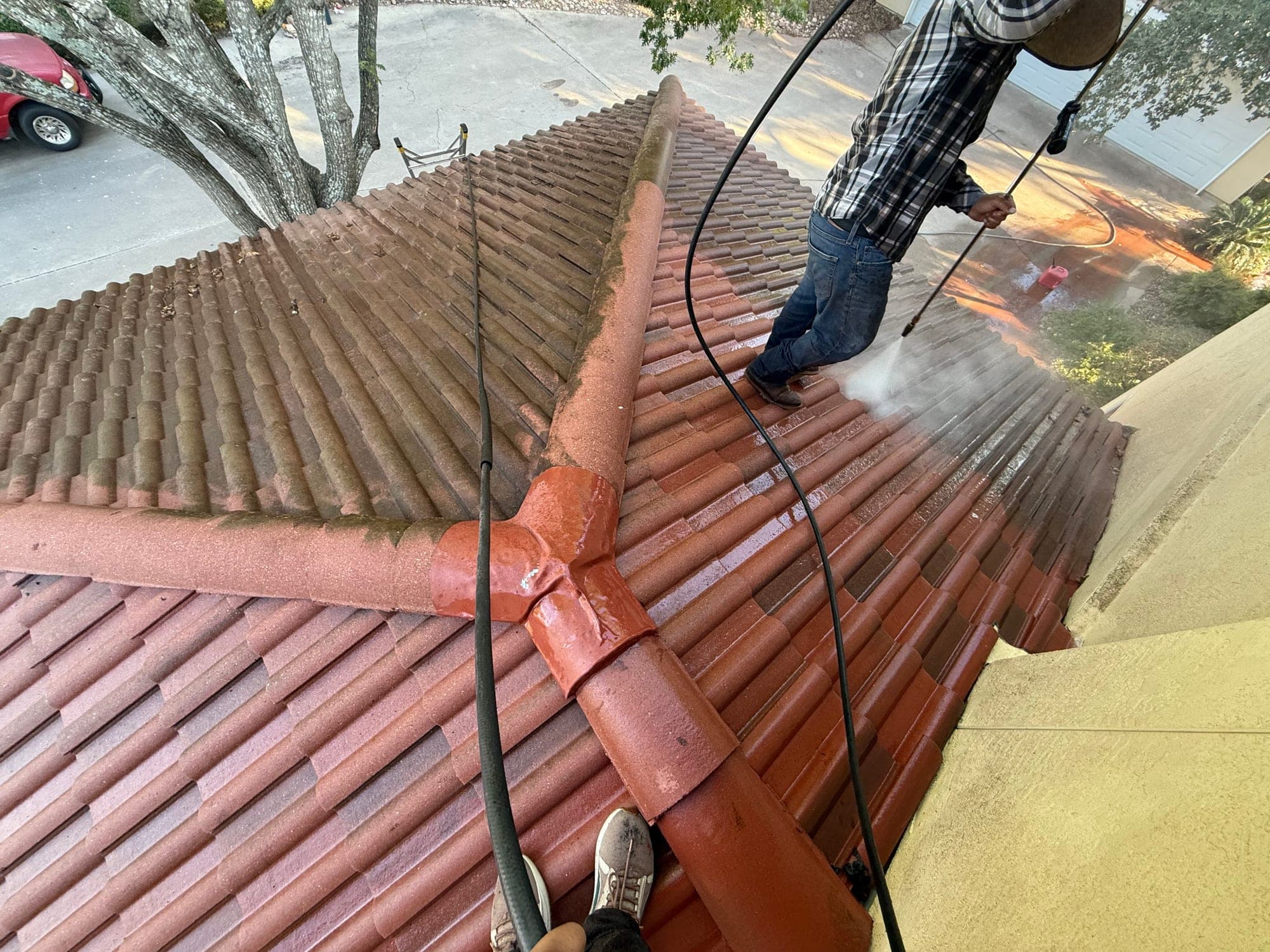 Concrete tile roof mid pressure wash, a sharp clean line separating washed tile from staining