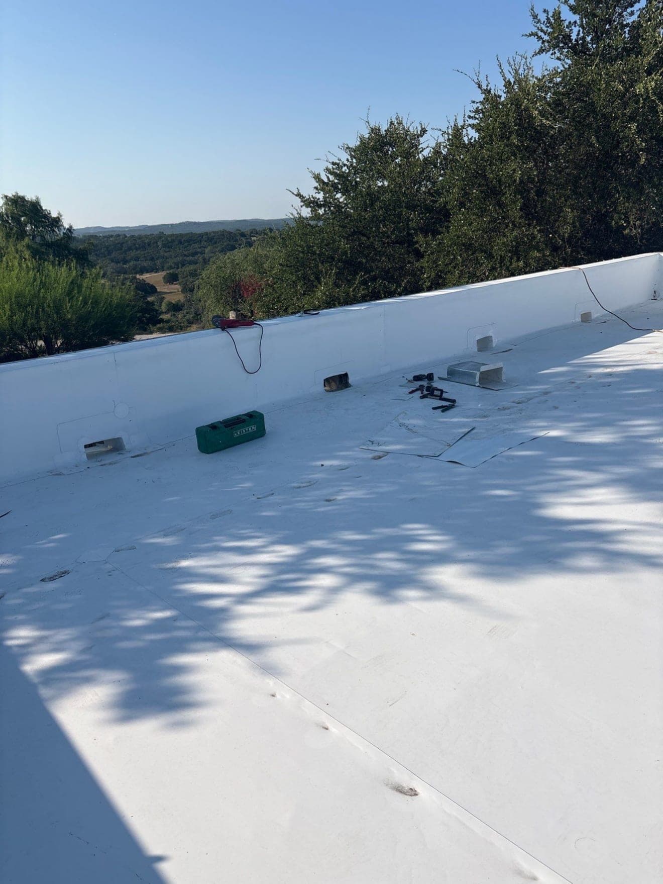 Completed white single-ply membrane roof across a full commercial deck, parapet wall running the length of it