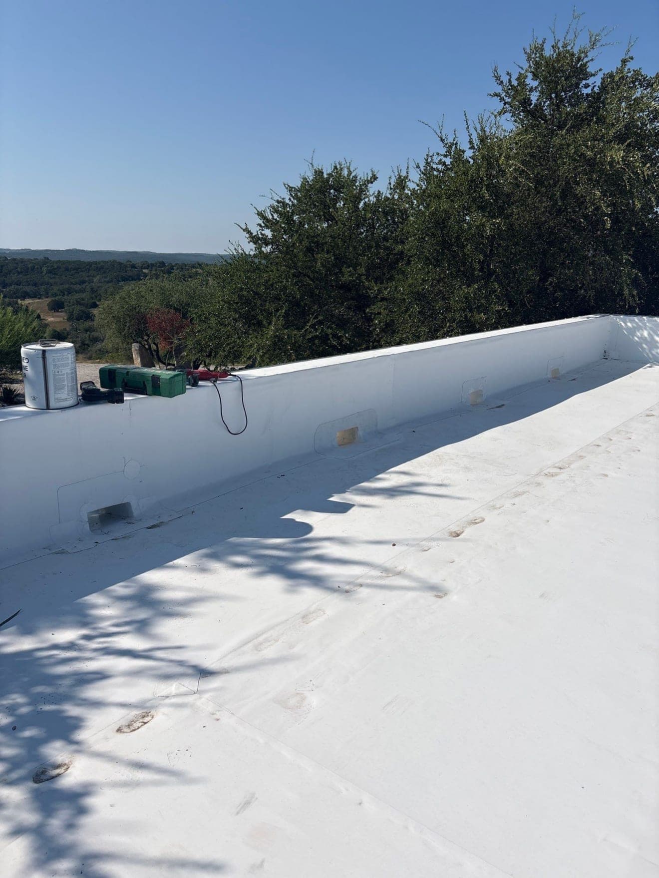 Single-ply membrane run up and over a parapet wall, welded corner returns and scuppers set through the wall