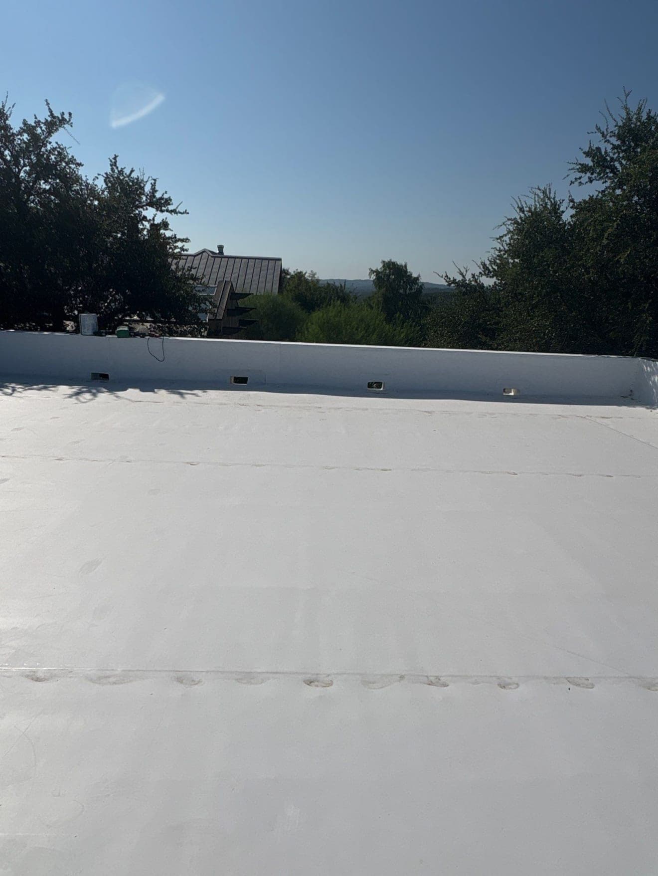 Scuppers set through a membrane-wrapped parapet wall with sealed metal sleeves, finished field beyond
